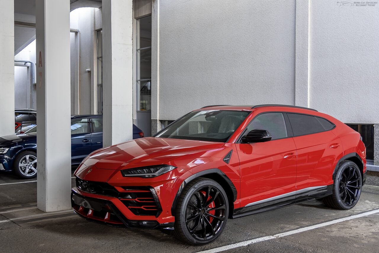 Lamborghini Urus vermelho estacionado numa garagem de prédio, entre colunas brancas